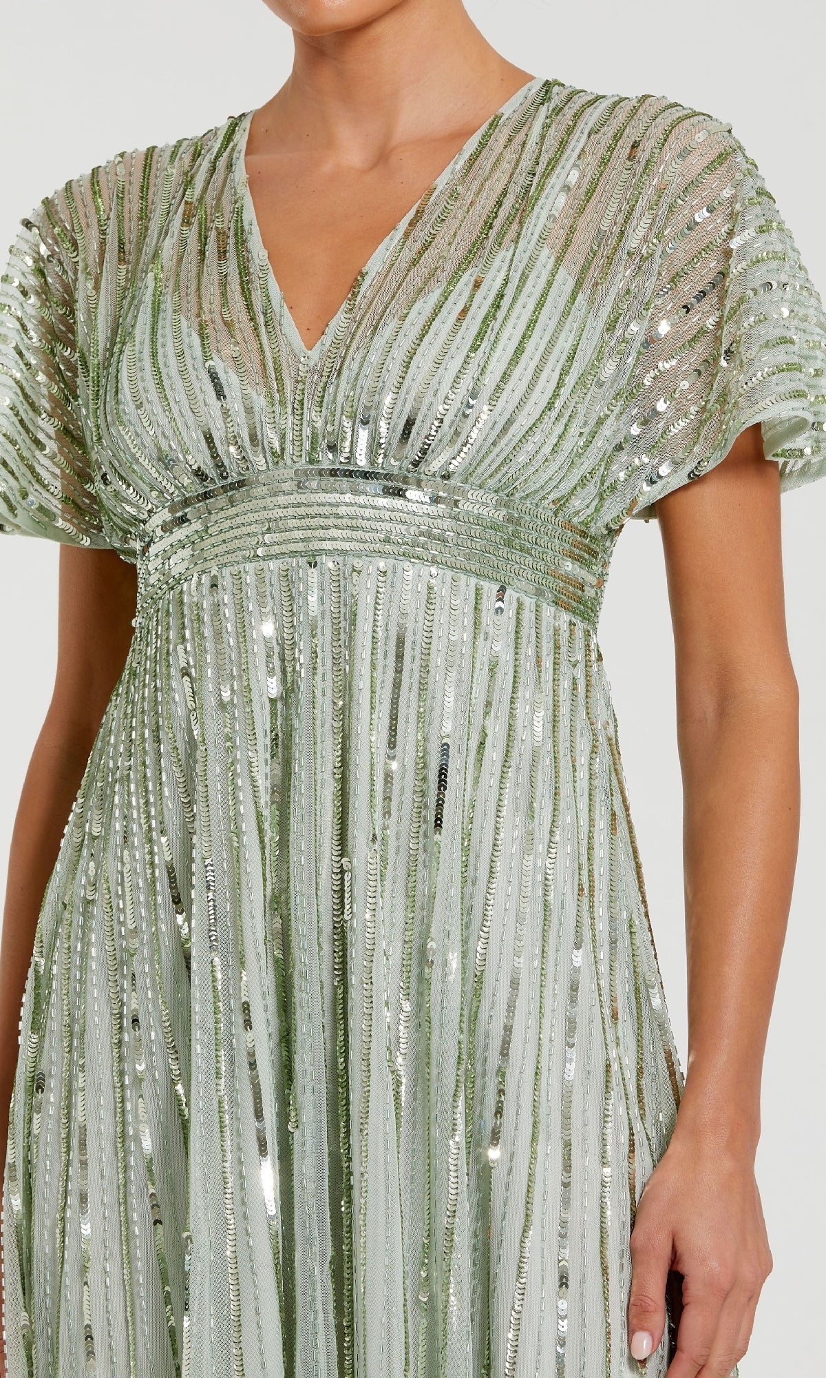 A woman wears the Mac Duggal 14007, a short sequin wedding-guest dress in light green with vertical stripes, short sleeves, and a V-neckline—ideal as a semi-formal party dress for special occasions.